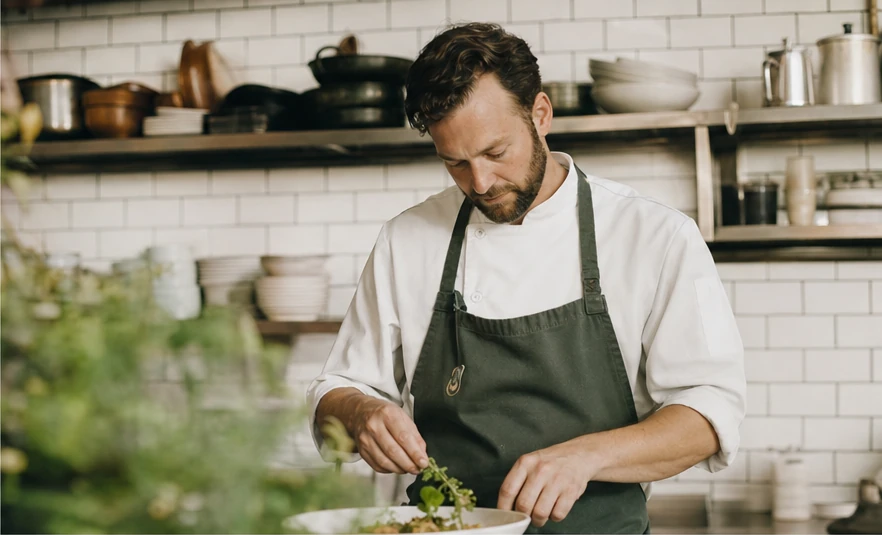 A chef plating a dish in a restaurant kitchen