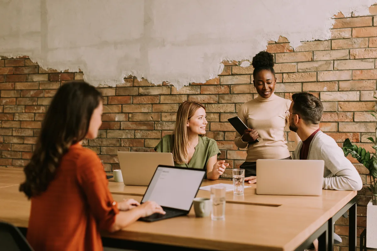 An accounting team collaborating around a table with laptops